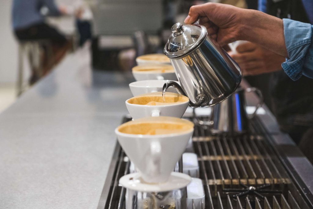 Barista připravuje několik porcí filtrované kávy